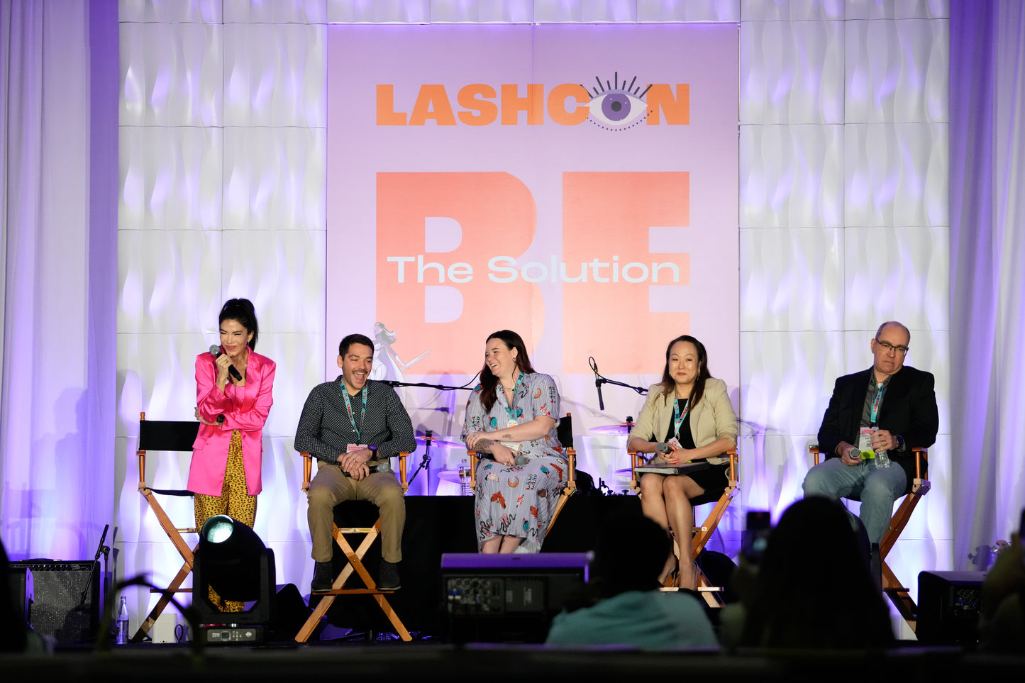 Panel of five speakers seated on stage at LashCon event with large backdrop displaying "LashCon B3 The Session" text.